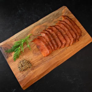 Sliced pastrami lox on a cutting board with spices